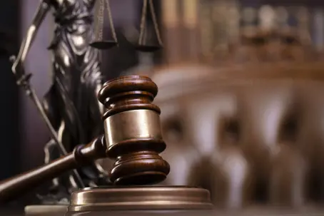 gavel on a stand with the scales of justice behind it